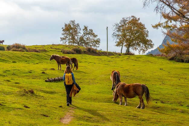 Une jeune femme dans la montagne Erlaitz avec des chevaux en liberté dans la ville d'Irun, Gipuzkoa. pays Basque