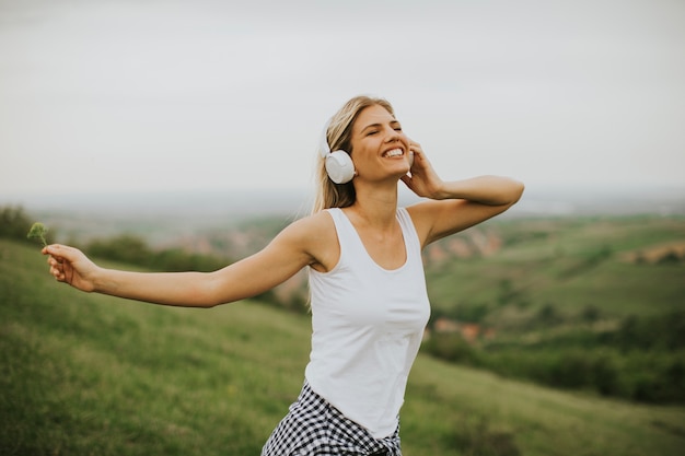 Jeune femme dans la nature, écouter de la musique sur des écouteurs