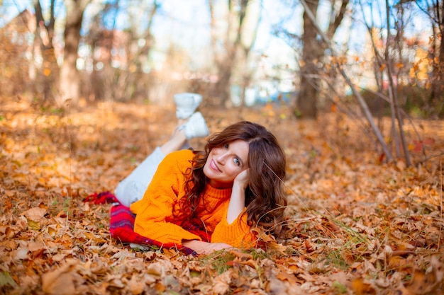 Une jeune femme dans un parc d'automne dans un chandail orange