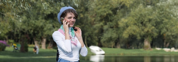 Jeune femme dans le parc parle par téléphone portable Portrait de jolie fille à la française