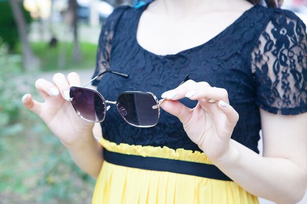 Jeune femme dans le parc tenant des lunettes de soleil