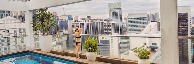 Jeune femme dans la piscine parmi les gratte-ciel et la grande ville Détendez-vous dans la grande ville Reposez-vous du stress BANNIÈRE FORMAT LONG