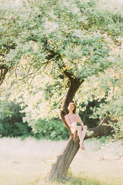 Jeune femme dans une robe d'été avec des pivoines dans l'arbre