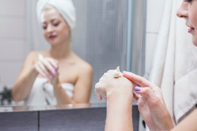 Jeune Femme Dans Une Salle De Bain Est Titulaire D'une Procédure Cosmétique Pour Améliorer La Beauté Et La Santé Dans Une Serviette