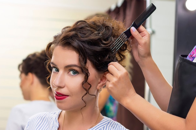 Jeune femme dans un salon de beauté. Le coiffeur fait la coiffure