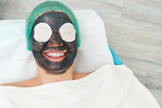 Jeune femme dans un salon de beauté avec un masque noir sur son visage