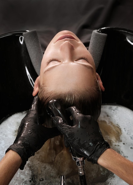 Jeune femme dans un salon de coiffure se teint les cheveux en blond et se lave la tête