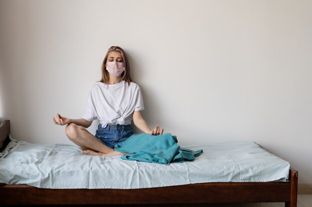 Jeune femme dans son lit avec un masque de protection