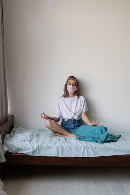 Jeune femme dans son lit avec un masque de protection