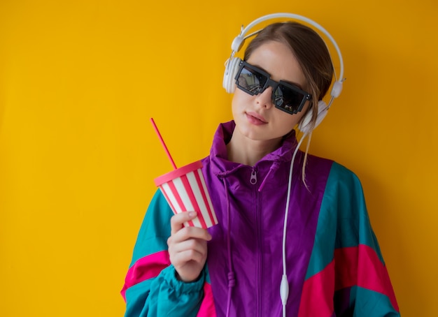 Jeune femme dans le style des années 90 avec une tasse et des écouteurs