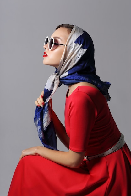 Jeune femme dans un style rétro avec lunettes de soleil et foulard en soie. Femme rétro de mode de style années 60.