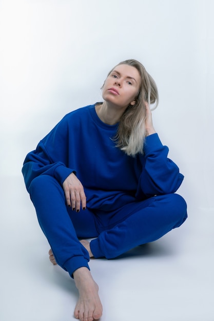 Photo jeune femme dans un sweat-shirt bleu et justaucorps sportswear posant sur fond blanc