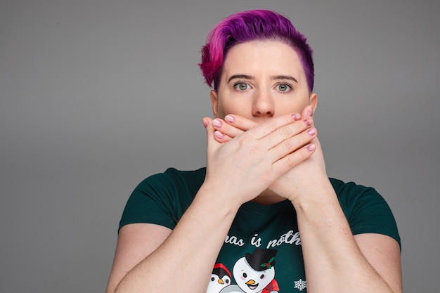 Jeune Femme Dans Un T-shirt Noir à La Peur Après Avoir Dit Quelque Chose Et En Plaçant Ses Deux Mains Pour Fermer La Bouche. Concept De Nouvel An