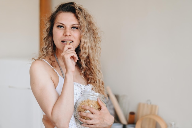 Jeune femme dans un tablier va cuisiner des pâtes