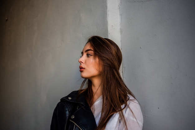 Jeune femme dans une veste en cuir noir et chemisier blanc