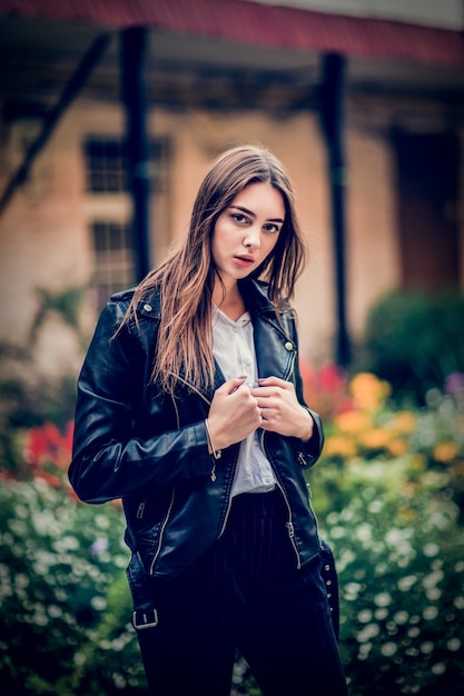 Jeune femme dans une veste en cuir noir dans le jardin