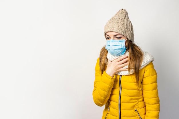 Jeune femme dans une veste jaune et un chapeau avec un masque médical isolé