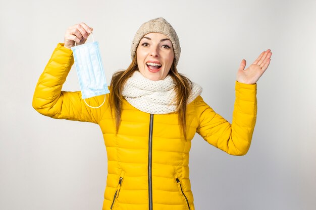 Jeune femme dans une veste jaune et un chapeau avec un masque médical