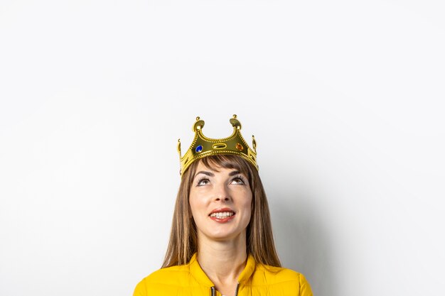 Jeune femme dans une veste jaune et une couronne d'or isolée