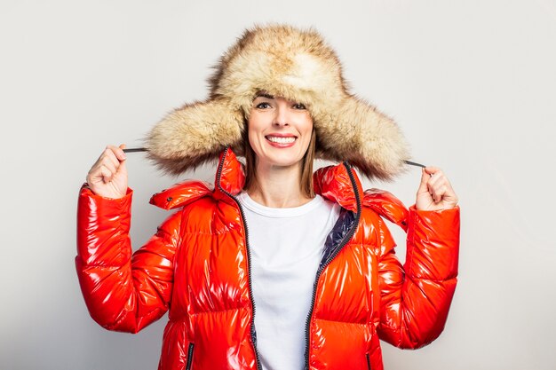 Jeune femme dans une veste rouge et un chapeau de fourrure isolé