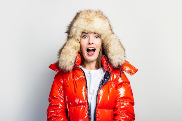 Jeune femme dans une veste rouge et un chapeau de fourrure isolé