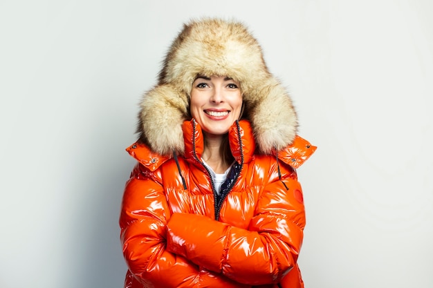 Jeune femme dans une veste rouge et un chapeau de fourrure isolé