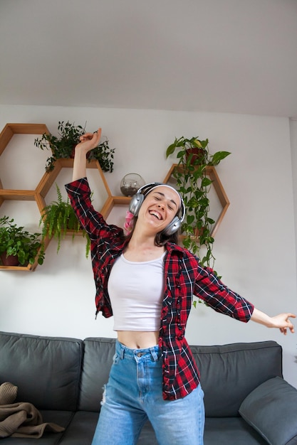 Jeune femme dansant en sirotant joyeusement en écoutant de la musique avec des écouteurs