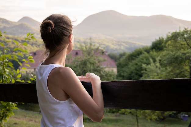 Jeune femme en débardeur blanc profite d'un magnifique paysage naturel avec vue sur la montagne