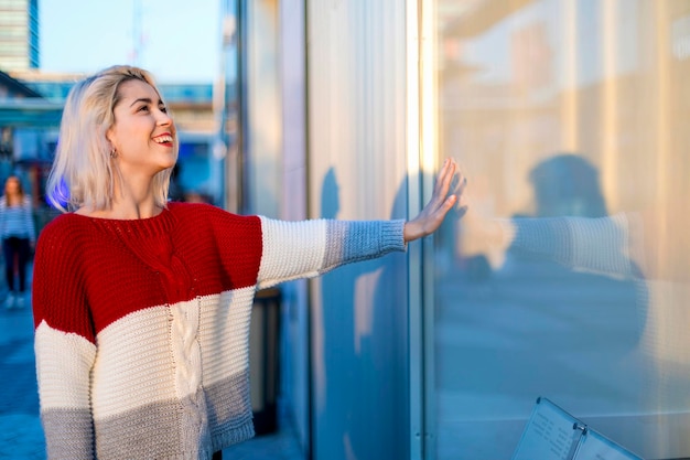 Une jeune femme debout contre la fenêtre.