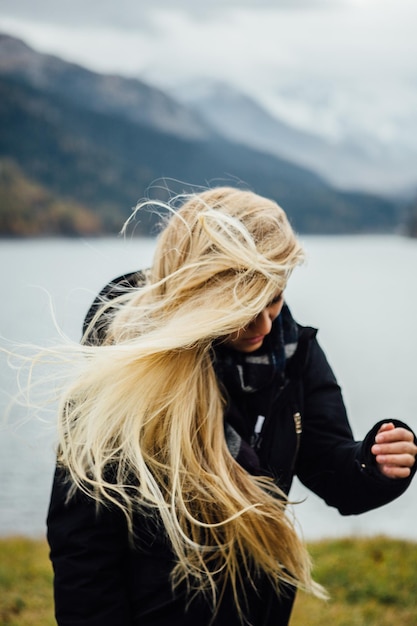 Une jeune femme debout contre le lac.