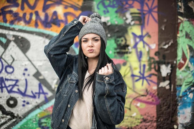 Une jeune femme debout contre un mur de graffitis