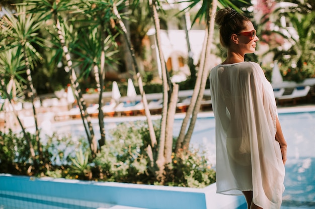 Jeune femme, debout, à côté de la piscine