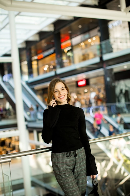 Jeune femme, debout, dans, centre commercial, conversation, sur, téléphone portable