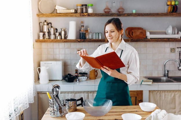 Jeune femme debout dans la cuisine avec livre de recettes. Cuisiner à la maison concept, style de vie.