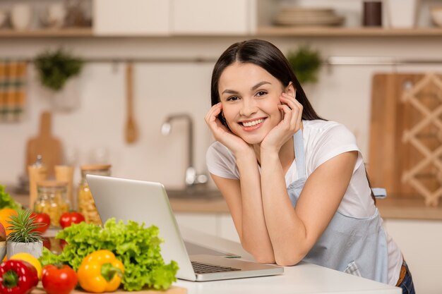 Jeune femme, debout, dans, cuisine, à, ordinateur portable