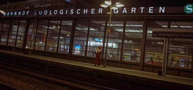 Une jeune femme debout dans une gare éclairée