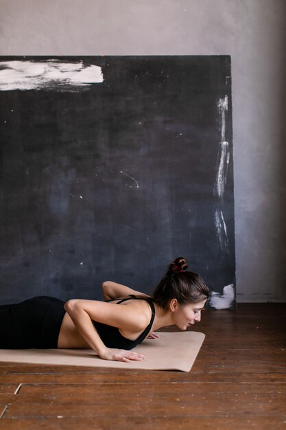 Jeune femme debout dans une position de yoga. Fille faisant du planka à bout de bras, pratiquez des exercices d'étirement au cours de yoga, faites des pompes à la maison.