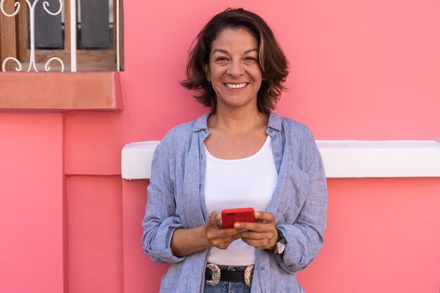 Jeune femme debout dans la rue tenant son smartphone