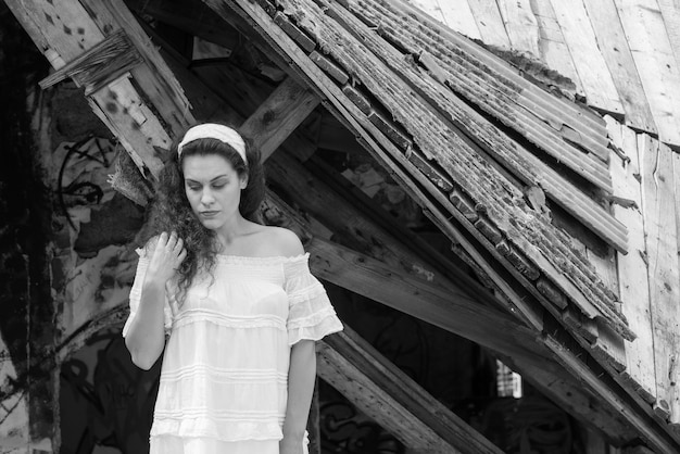 Photo une jeune femme debout devant une maison abandonnée.