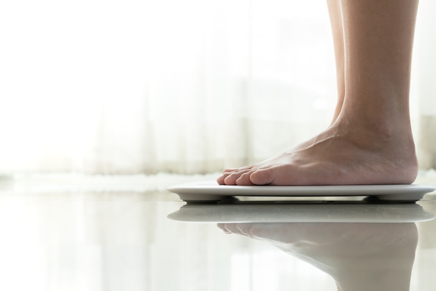 Jeune femme debout sur une échelle de poids numérique
