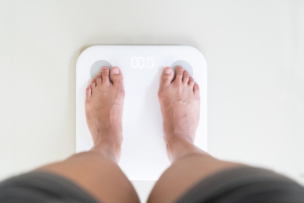 Jeune femme debout sur une échelle de poids numérique