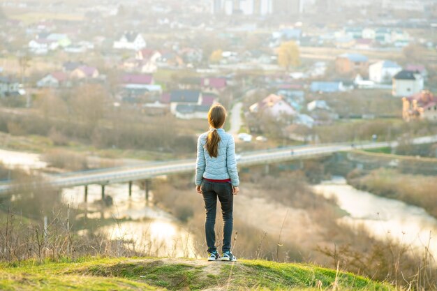 Jeune femme debout à l'extérieur, profitant de la vue sur la ville.