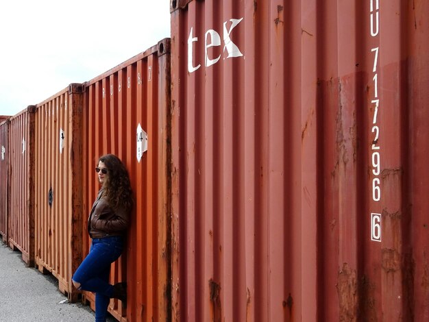 Photo une jeune femme debout près des conteneurs.