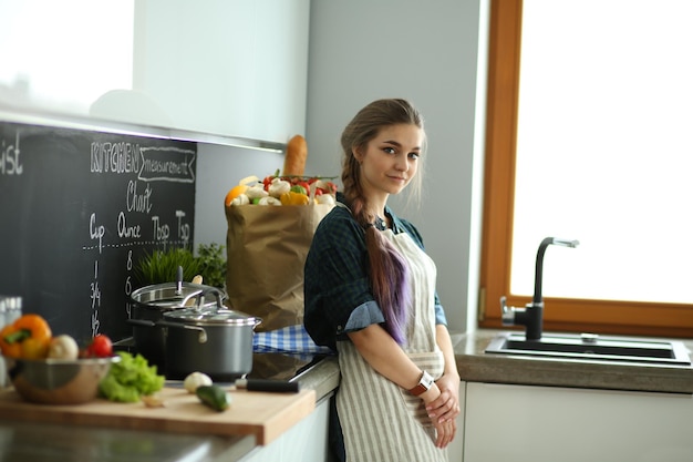 Jeune femme debout près du poêle dans la cuisine