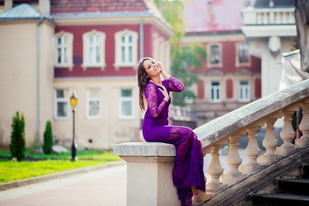 Jeune femme debout près des murs d'un ancien château. Fille de beauté à l'extérieur dans l'ancien château. Belle fille modèle en robe longue. Brunette appréciant les voyages. Femme heureuse gratuite.