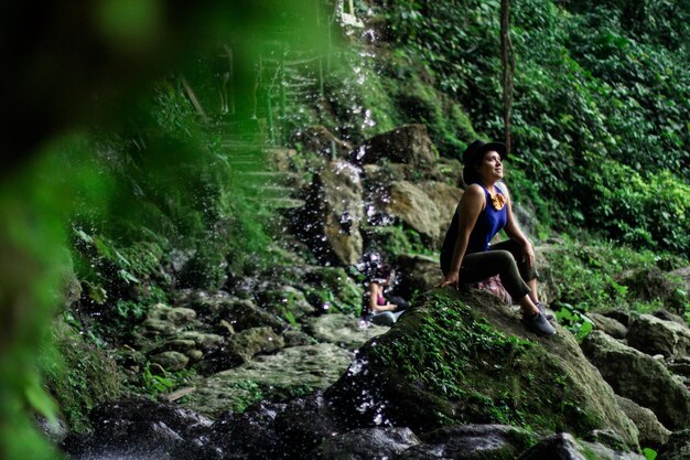 Photo une jeune femme debout sur un rocher dans la forêt