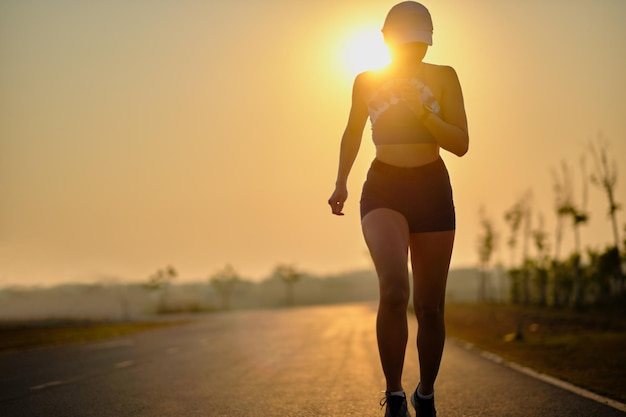 Une jeune femme debout sur la route contre le ciel au coucher du soleil