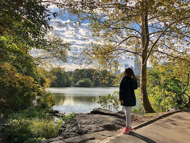 Une jeune femme debout sur la route près du lac au milieu des arbres