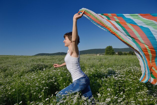Jeune femme debout sautant et courant sur un champ de blé avec un ciel bleu en arrière-plan le jour d'été représentant une vie saine et un concept d'agriculture
