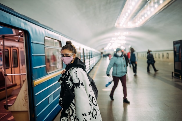 Jeune femme debout à la station en masque de protection médicale